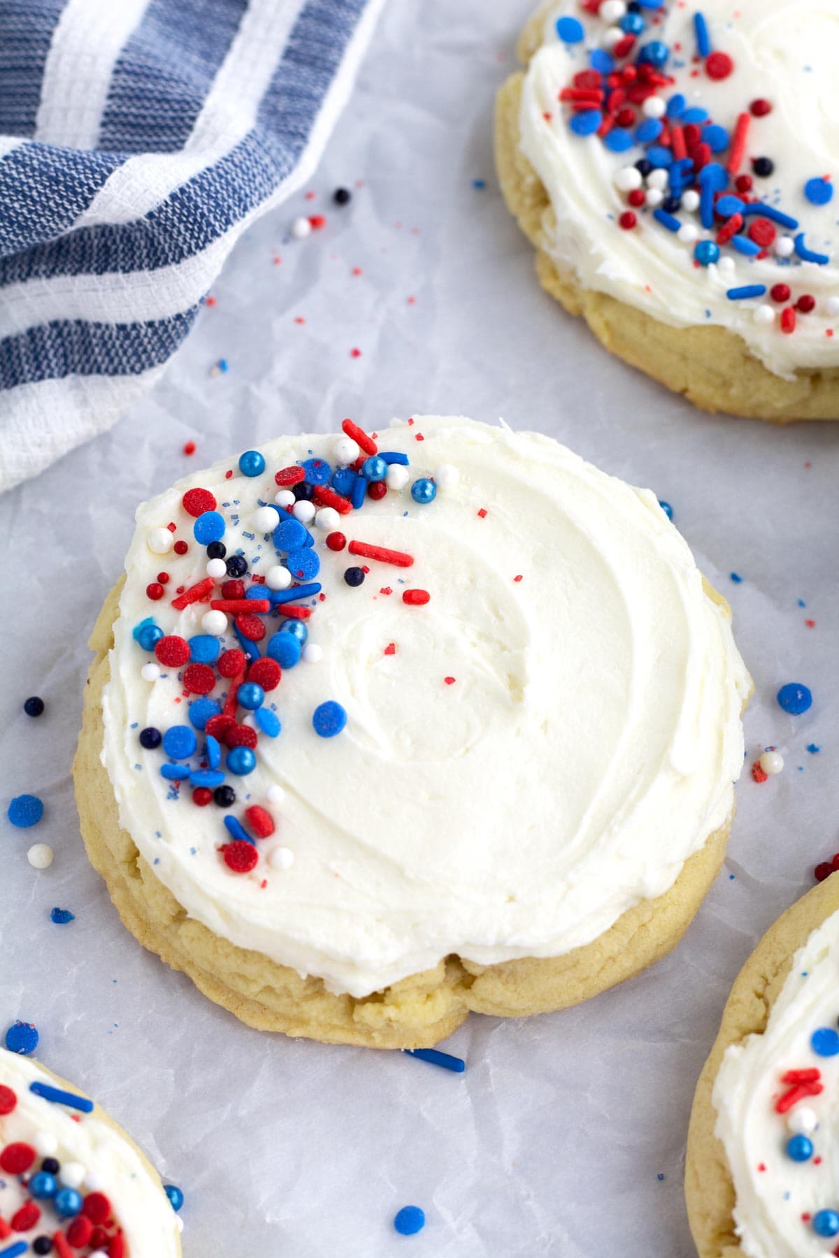 Giant sugar cookie with vanilla frosting and patriotic sprinkles on crumpled parchment.