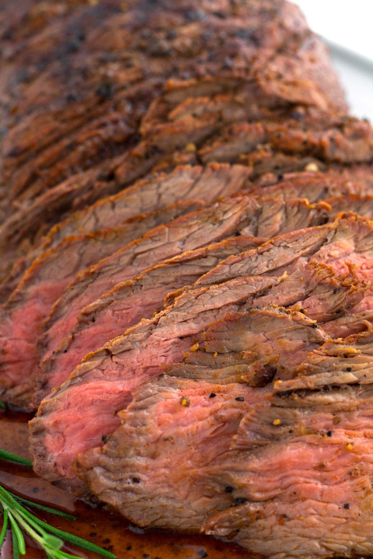 Layered slices of tri-tip roast with smoked flavor on serving plate.