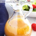 Clear jar of vinaigrette with blue towel on side, salad in background, and text overlay.