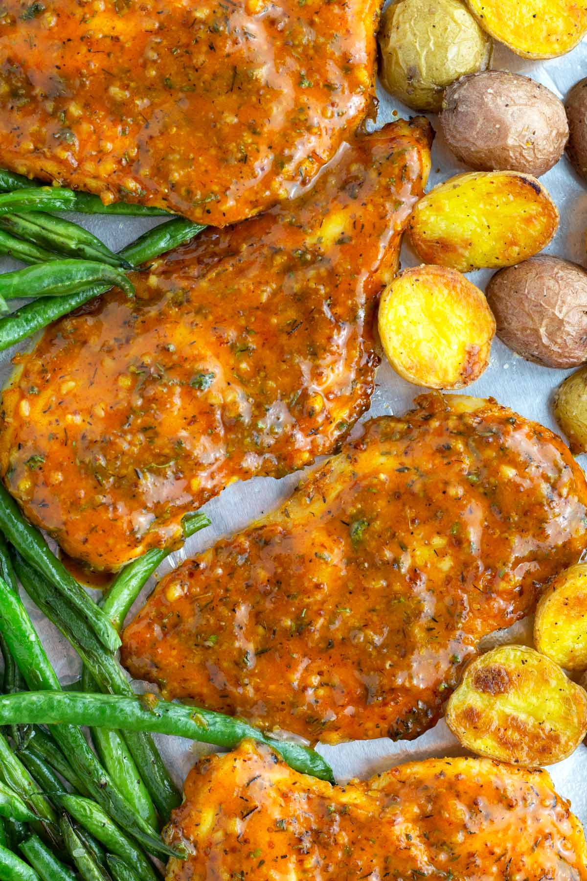 Overhead view of sheet pan chicken breasts, green beans, and potatoes.