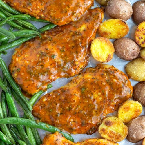 Overhead view of honey mustard chicken breasts, green beans, and potatoes cooked on a sheet pan.