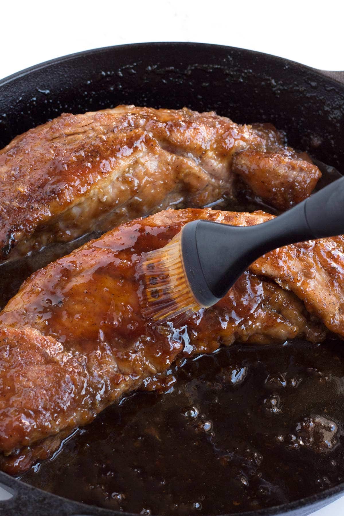 Brushing maple mustard glaze onto pork as it cooks.