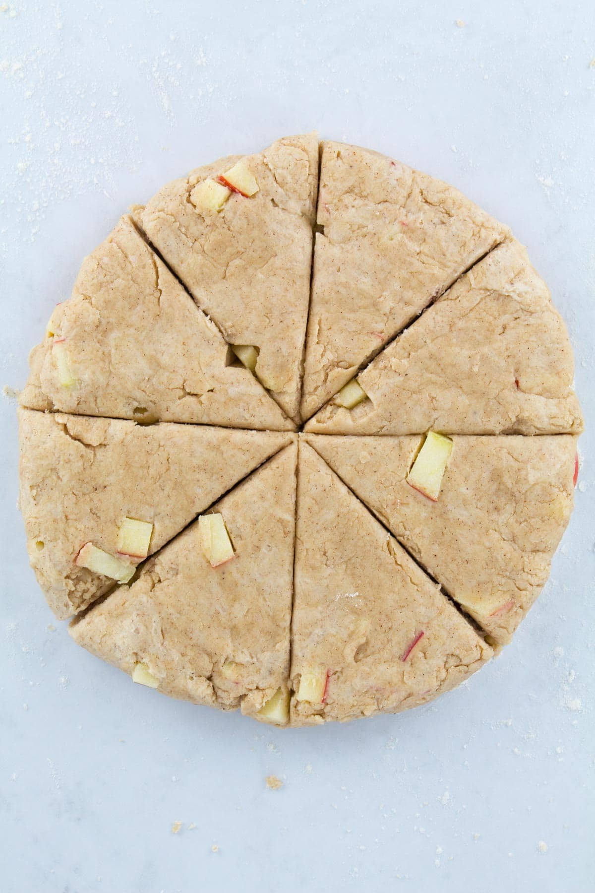 Overhead of scone dough patted into a circle and cut into eight wedges.