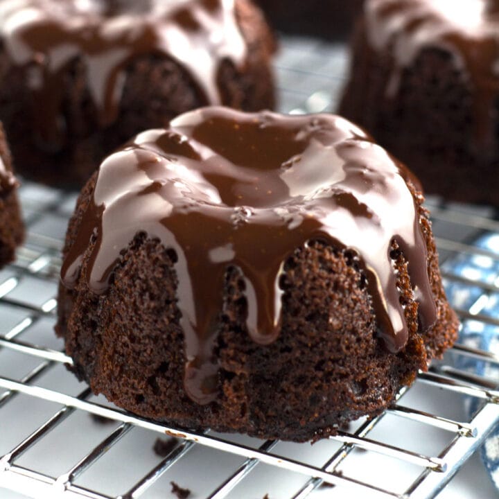 Individual mini bundt cakes lined up on a wire cooling rack.