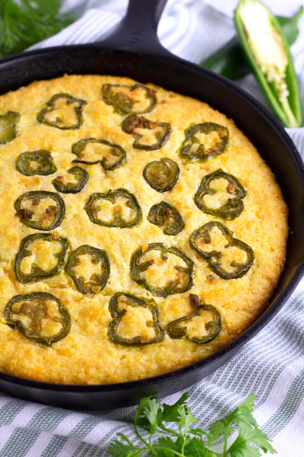 Partial pan of cornbread baked with jalapenos in pan.