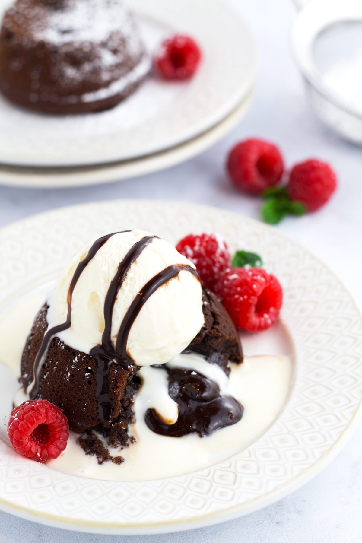 Lava cakes with molten center spilling out and a scoop of ice cream on a plate.