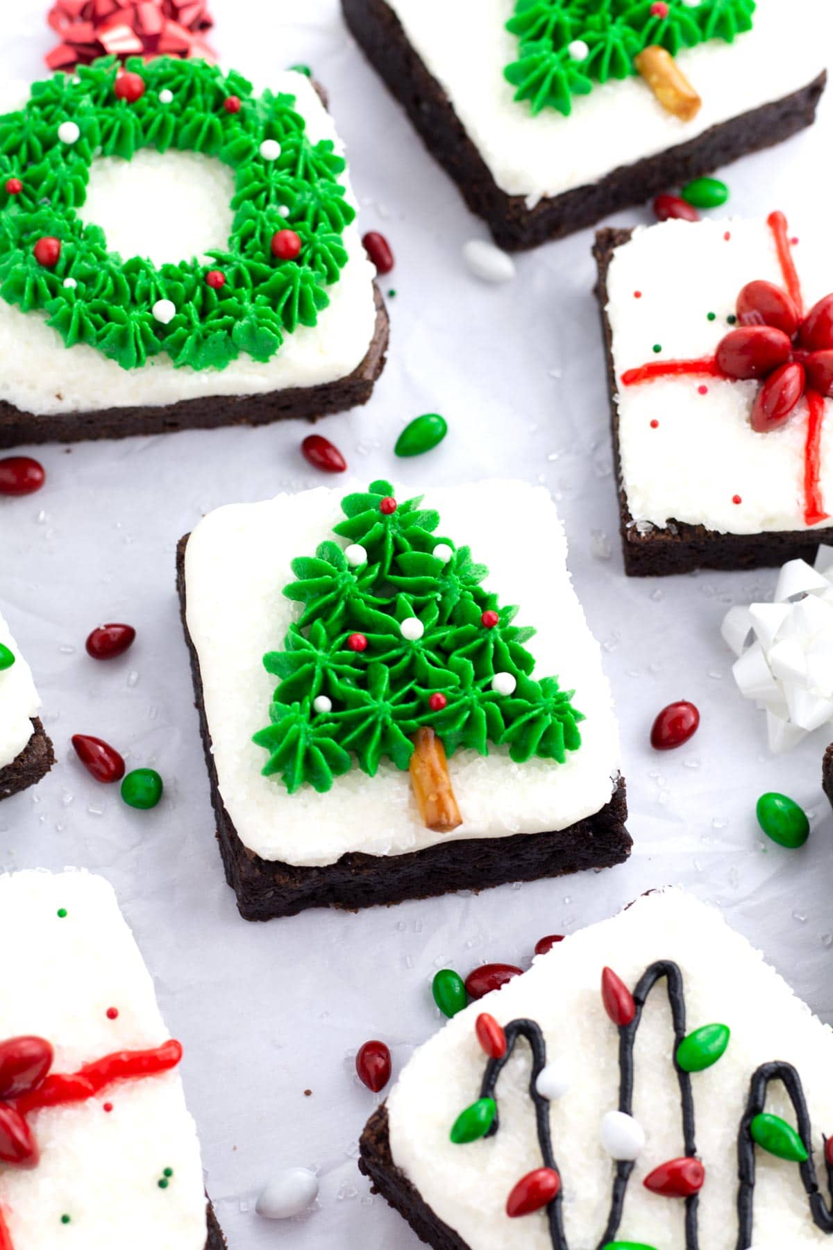 Christmas tree brownie on parchment paper with other brownies peaking into the scene.