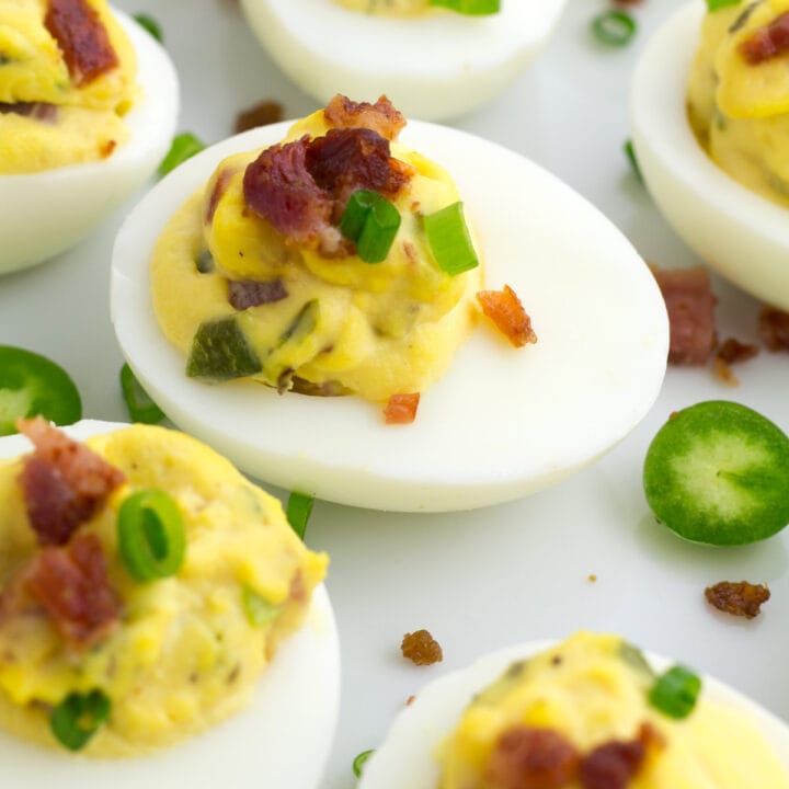 Jalapeno eggs that are both spicy and smokey on platter with extra bacon and peppers.