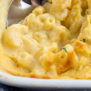 Cheesy baked mac and cheese sauce on serving spoon after baked in the oven.