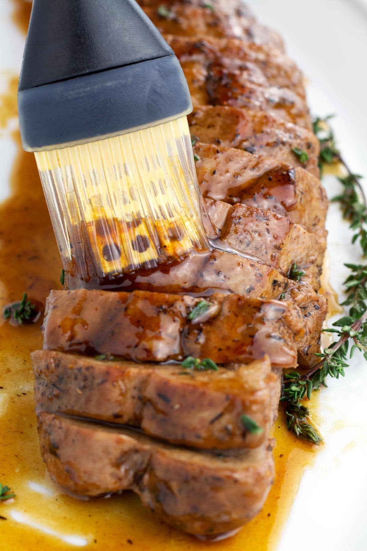 Silicon brush coating pork tenderloin with honey butter sauce.