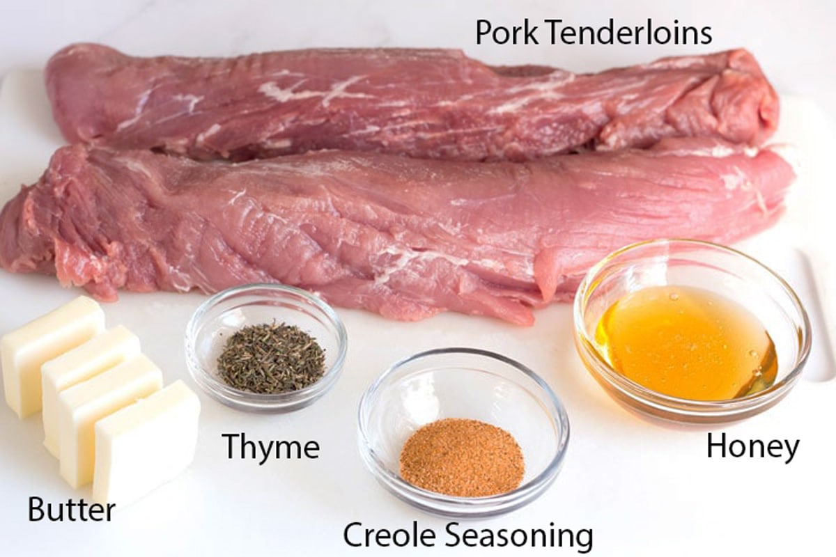 Ingredients to make pork tenderloin in cast iron skillet on white counter top.