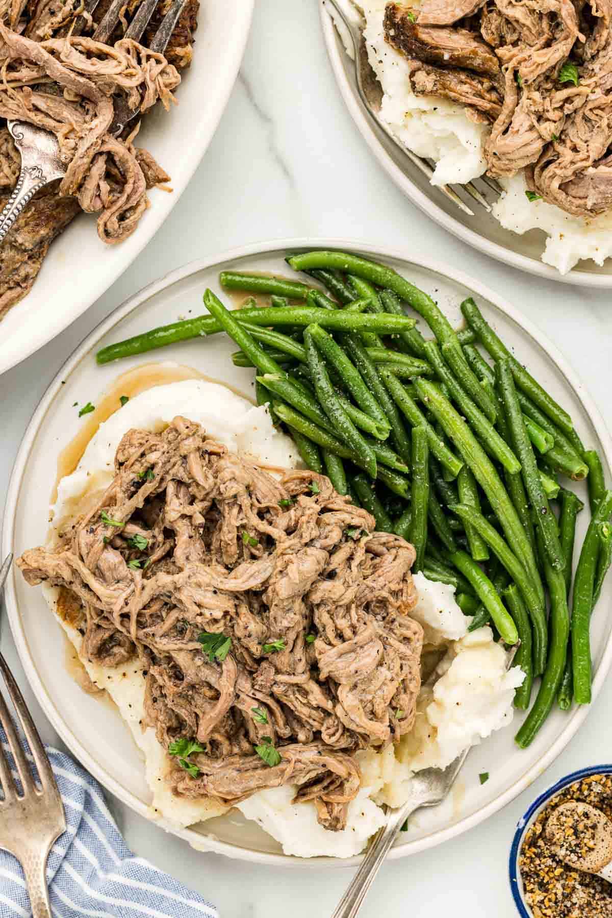 Close up of tender slow cooker tri-tip roast drizzled with gravy and fresh parsley.
