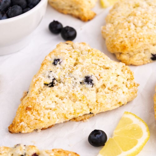 A baked lemon scone with blueberries on parchment.