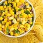 A bowl of mango habanero salsa surrounded by tortilla chips.