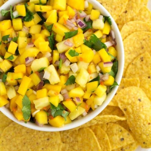 A bowl of mango habanero salsa surrounded by tortilla chips.