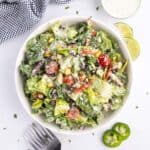 Mexican salad in a white bowl with two forks beside it.