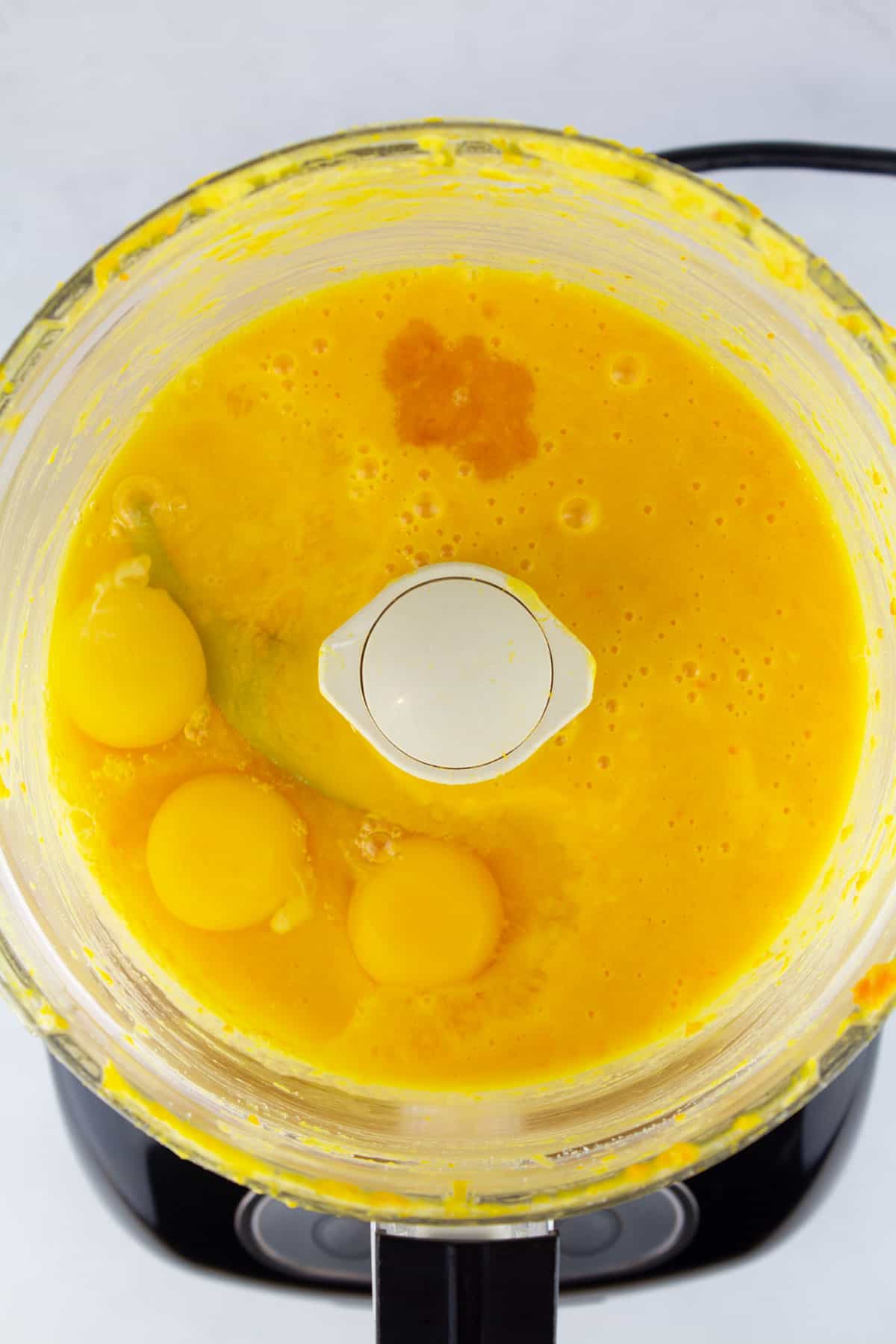 Overhead of food processor with eggs added to cake batter.