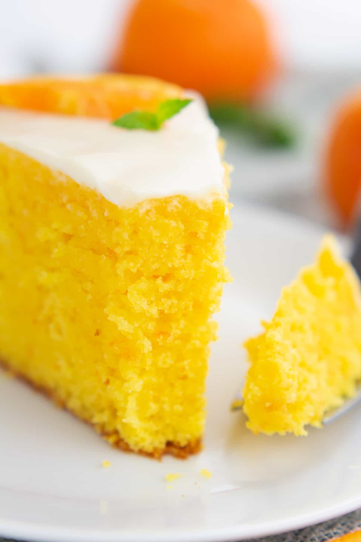 Up close view of a slice of clementine cake with a bite removed on a fork.