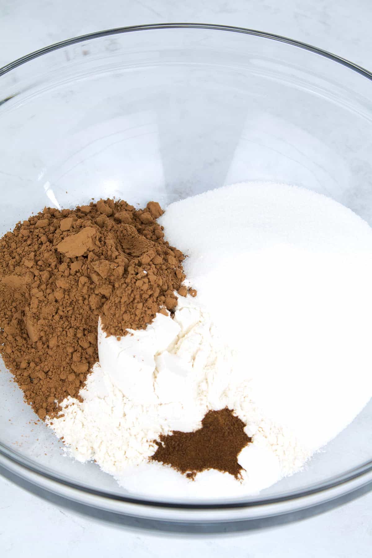 Dry ingredients for cake batter unmixed in a clear glass bowl.