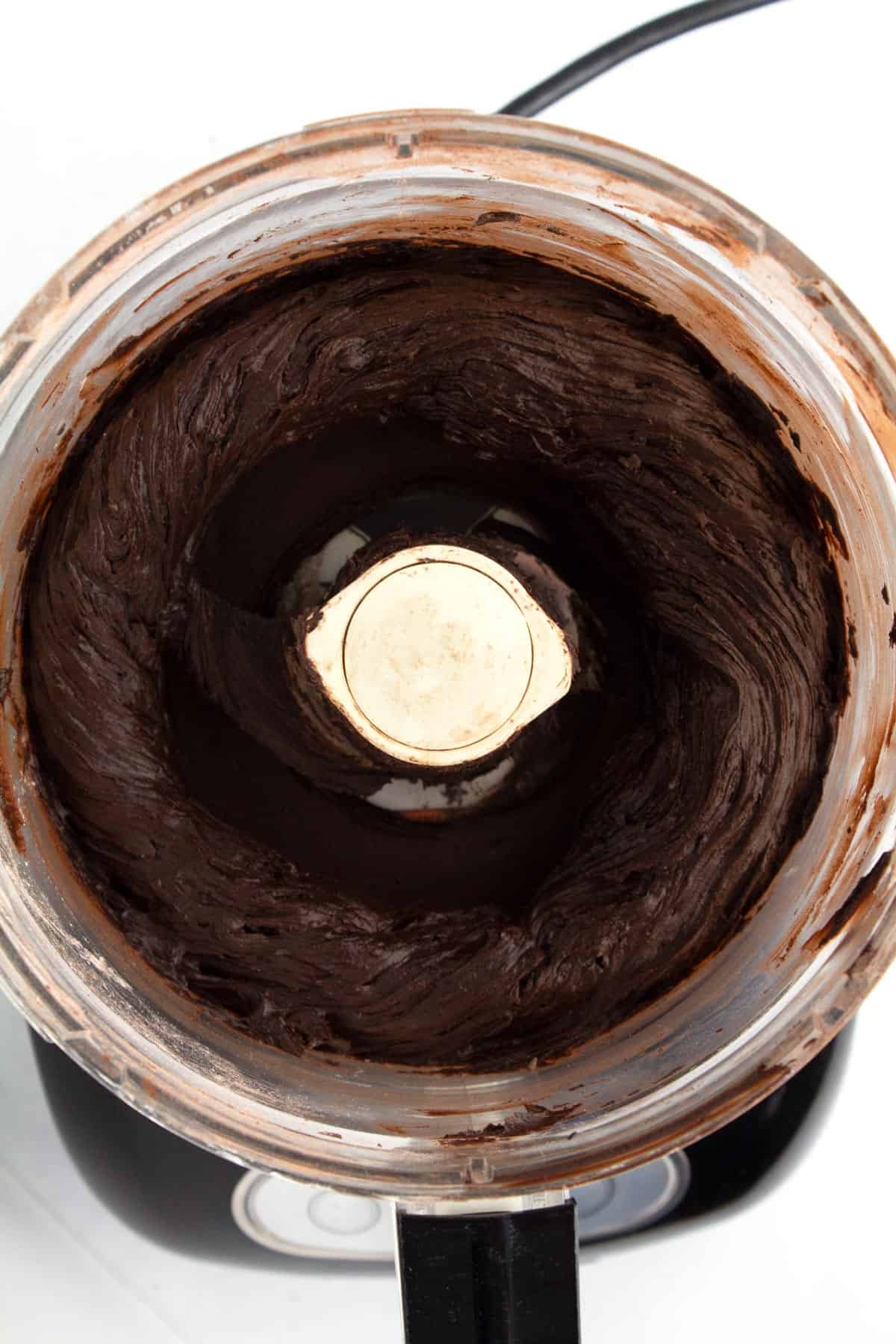 Chocolate frosting in a food processor after combining the first ingredients.