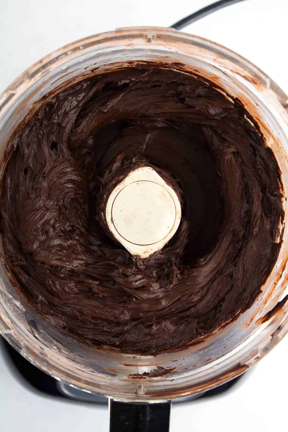 Chocolate frosting in a food processor after combining with corn syrup.