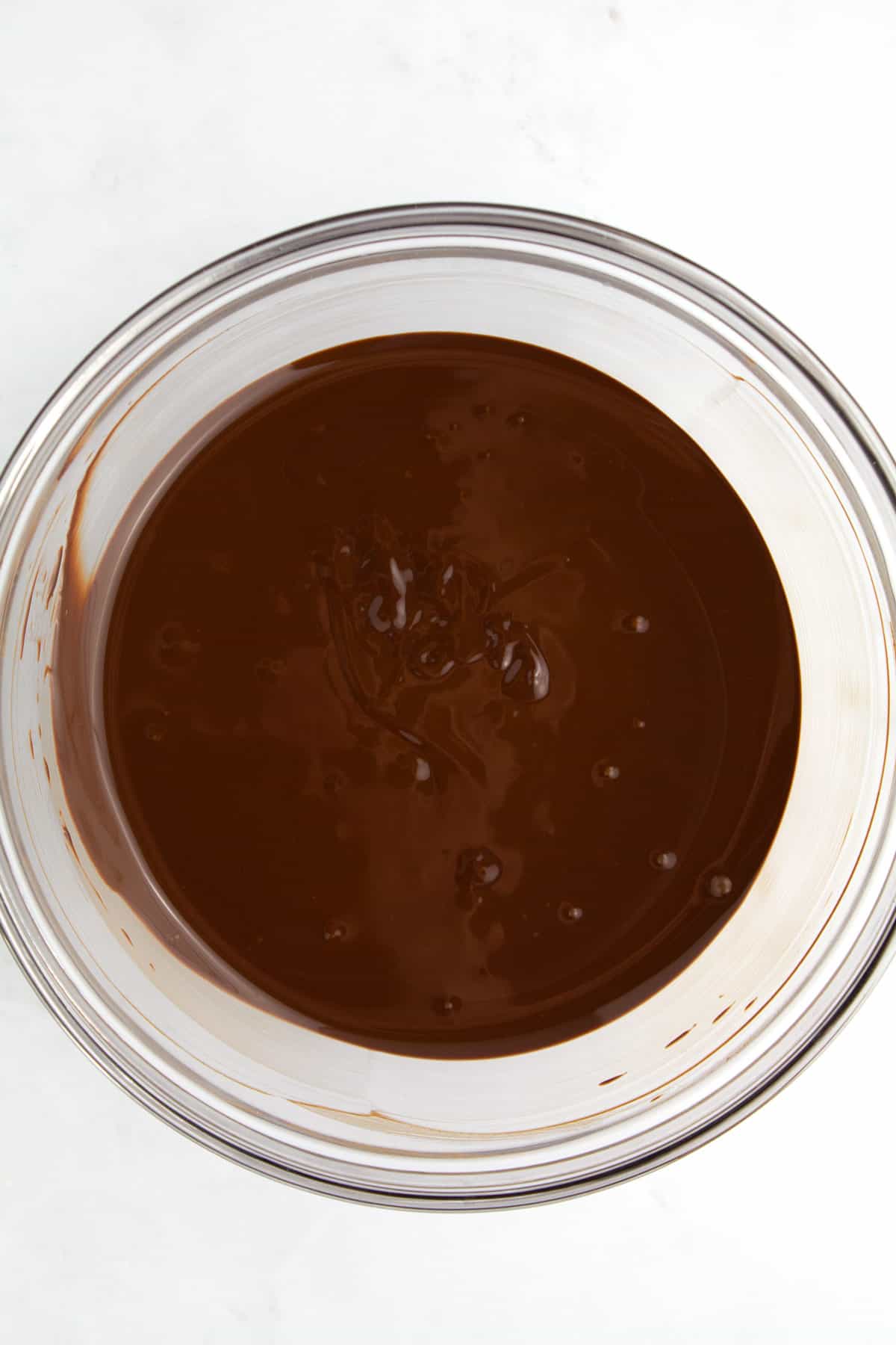Melted chocolate in a clear glass bowl.