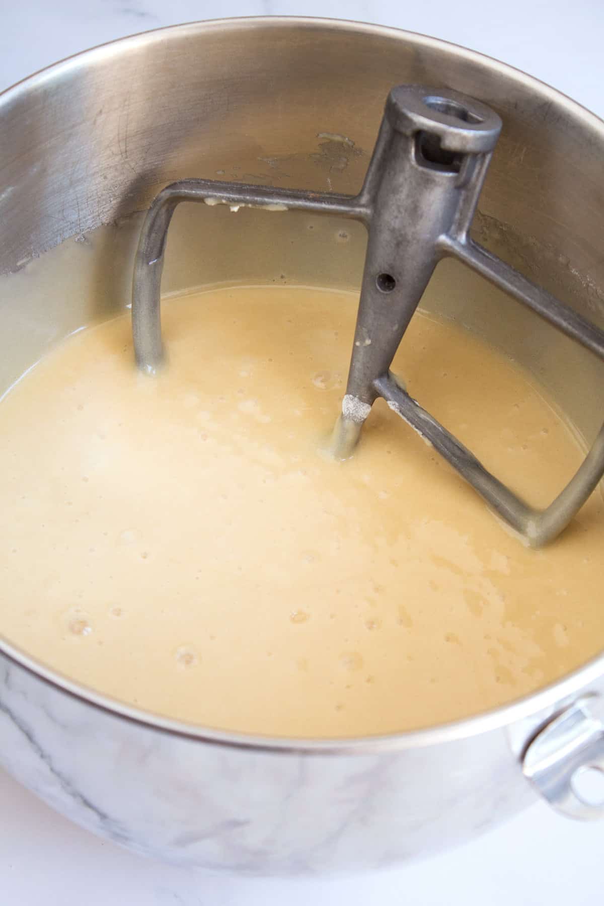 Stainless steel mixing bowl full of cake batter before the chocolate has been added.