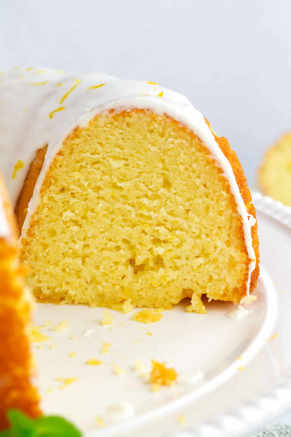 Close view of the inside of a sliced lemon bundt cake on a white cake platter.