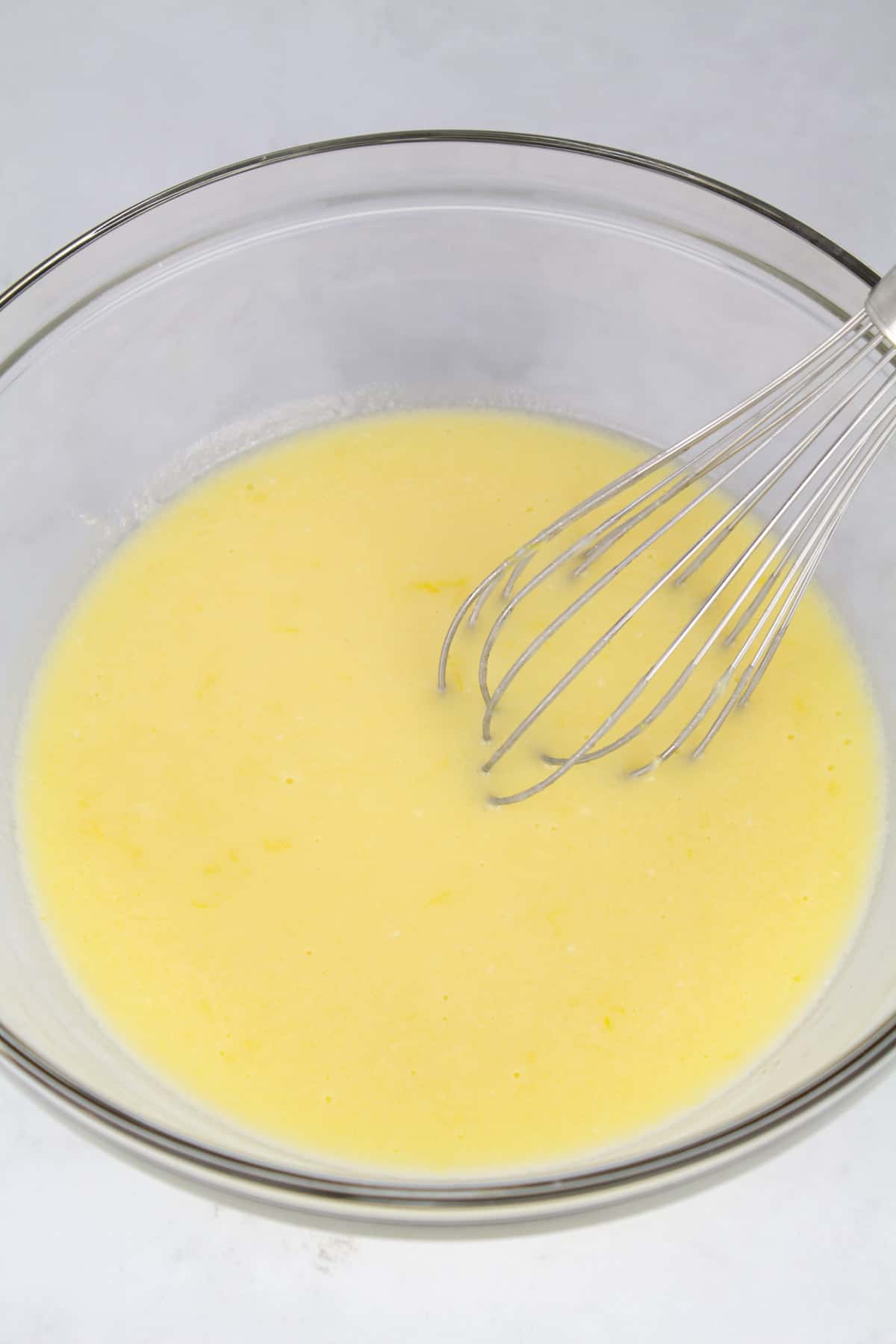 Wet ingredients in a small glass bowl with a whisk sitting in the back of the bowl.