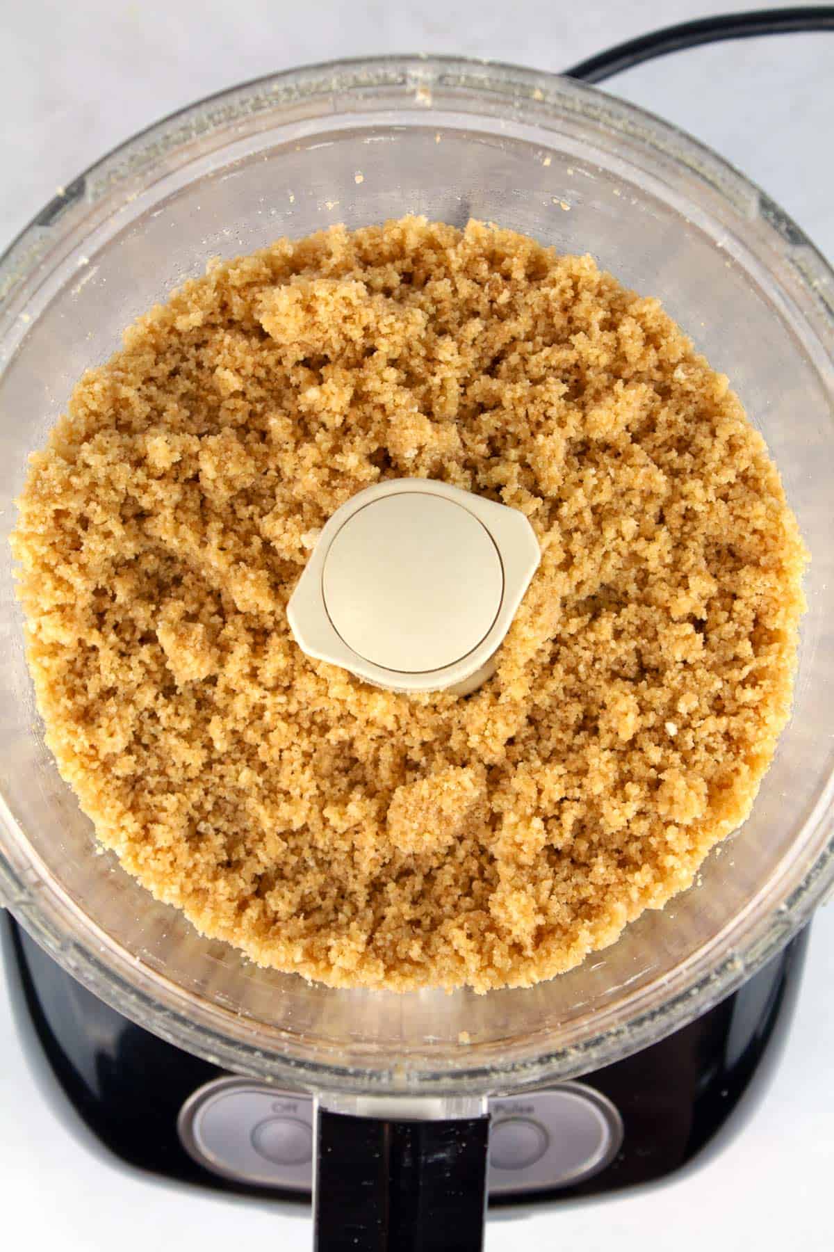An overhead view of the crust ingredients blended in a food processor.