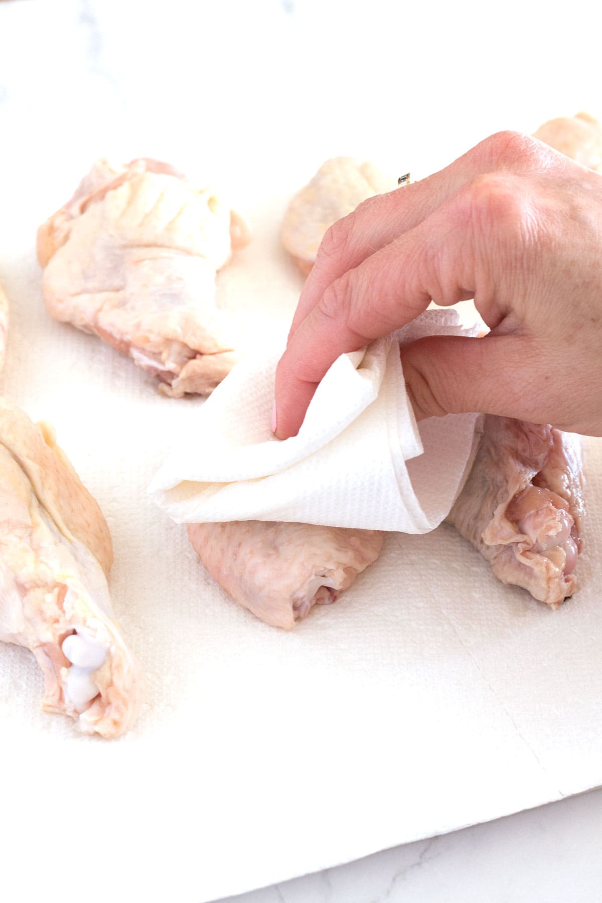 Drying chicken wings with paper towels for optimum crispiness.