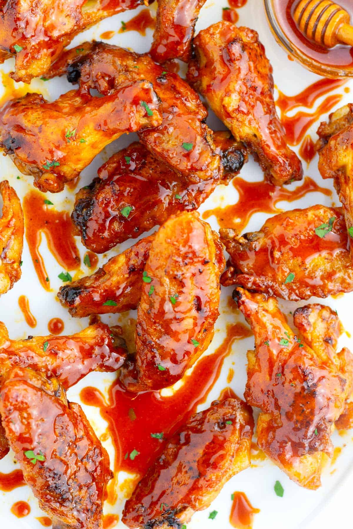 Crispy chicken wings on platter with hot honey sauce.