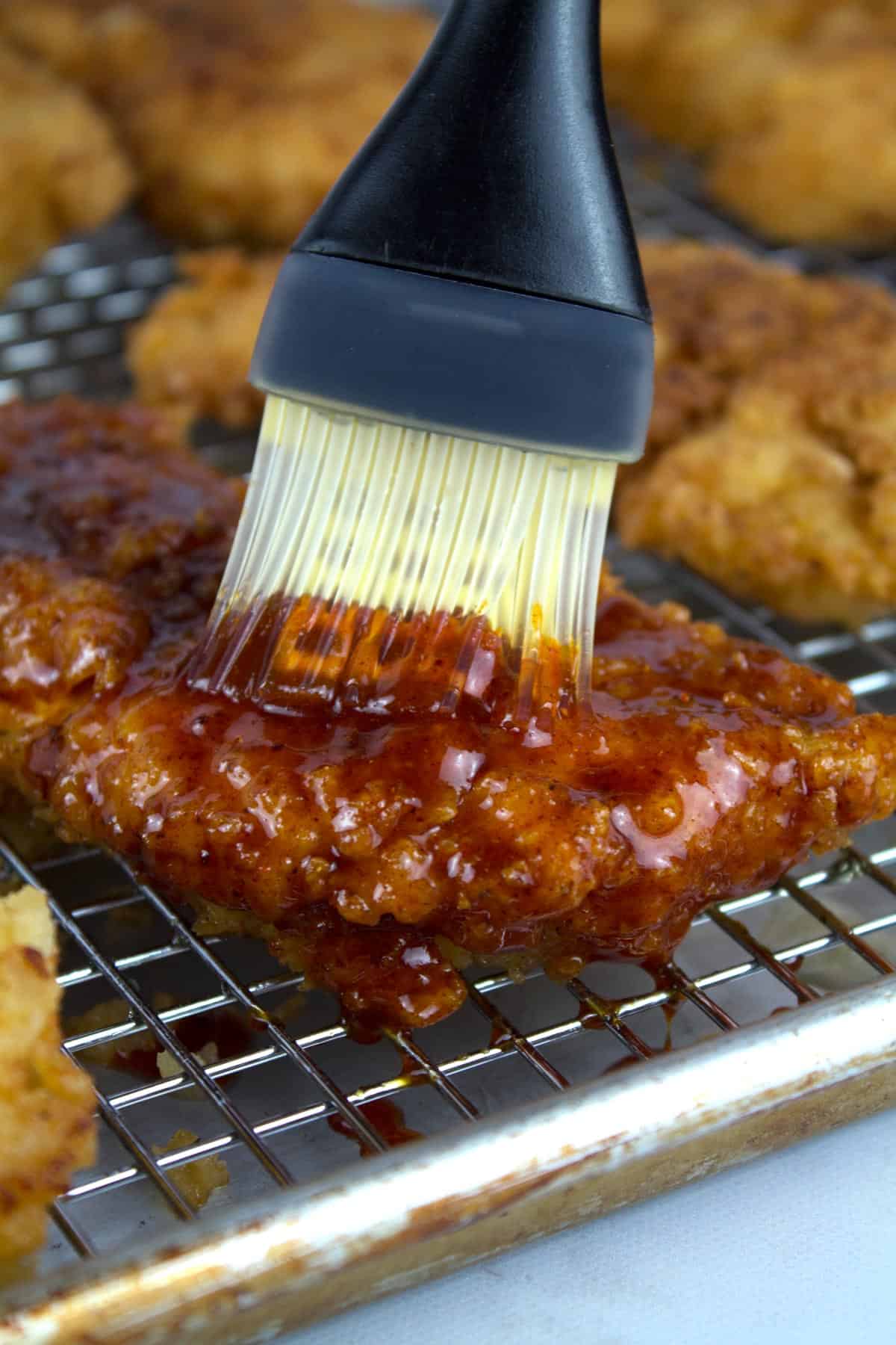 Brushing crispy chicken cutlet with hot honey sauce.