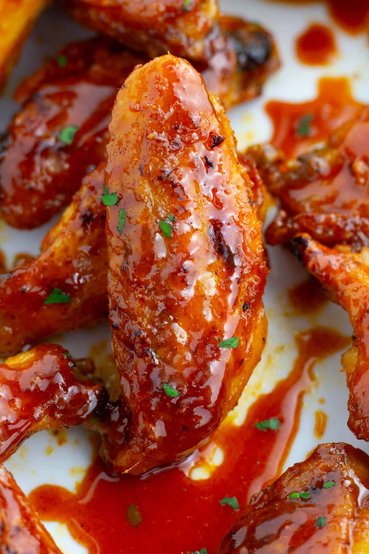 Glazed hot honey chicken wings displayed on white plate.