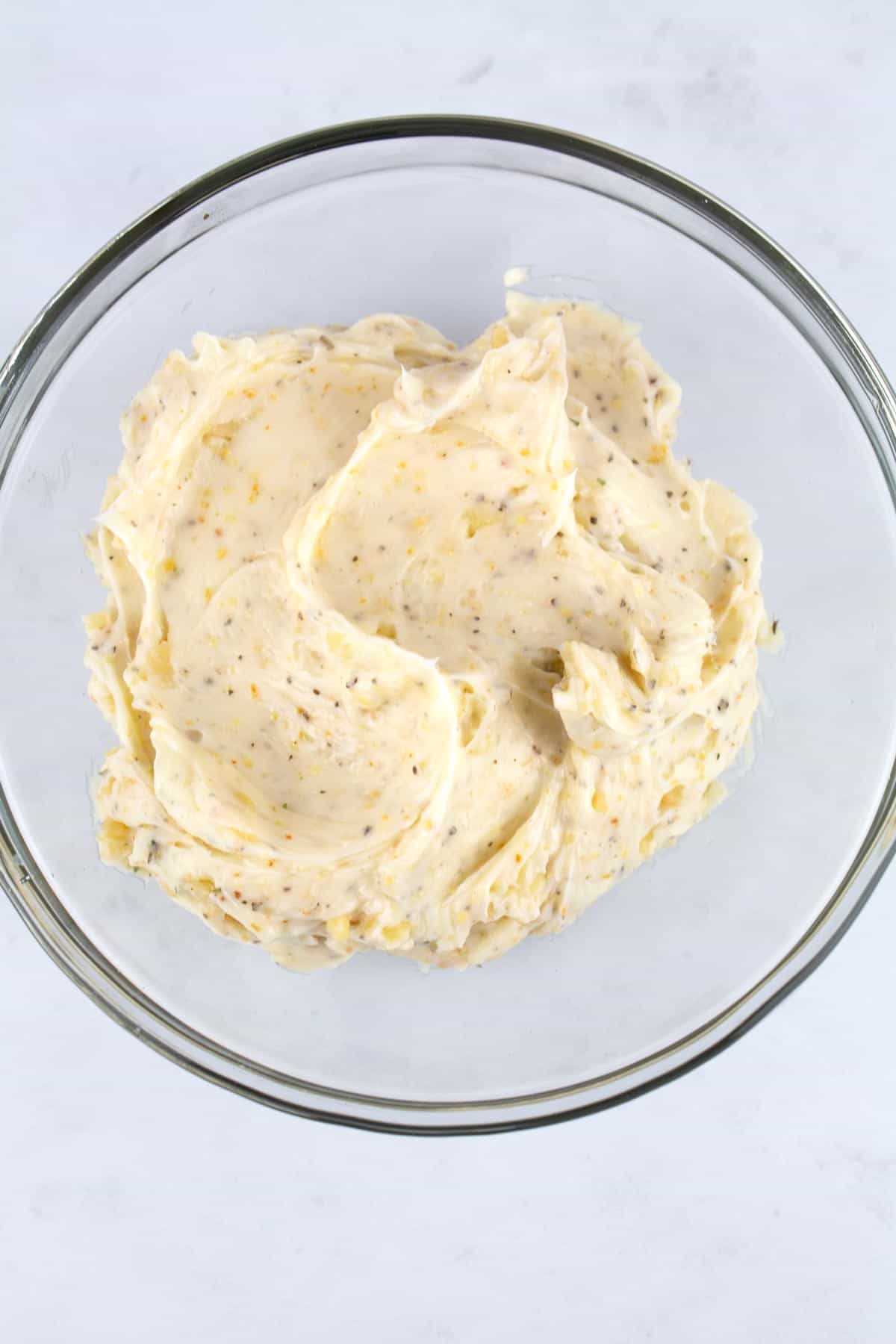 Flavored butter with herbs and seasonings in a bowl.