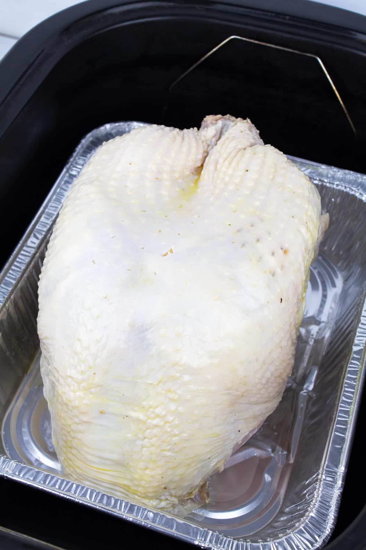Turkey breast in foil pan set down in roaster oven.