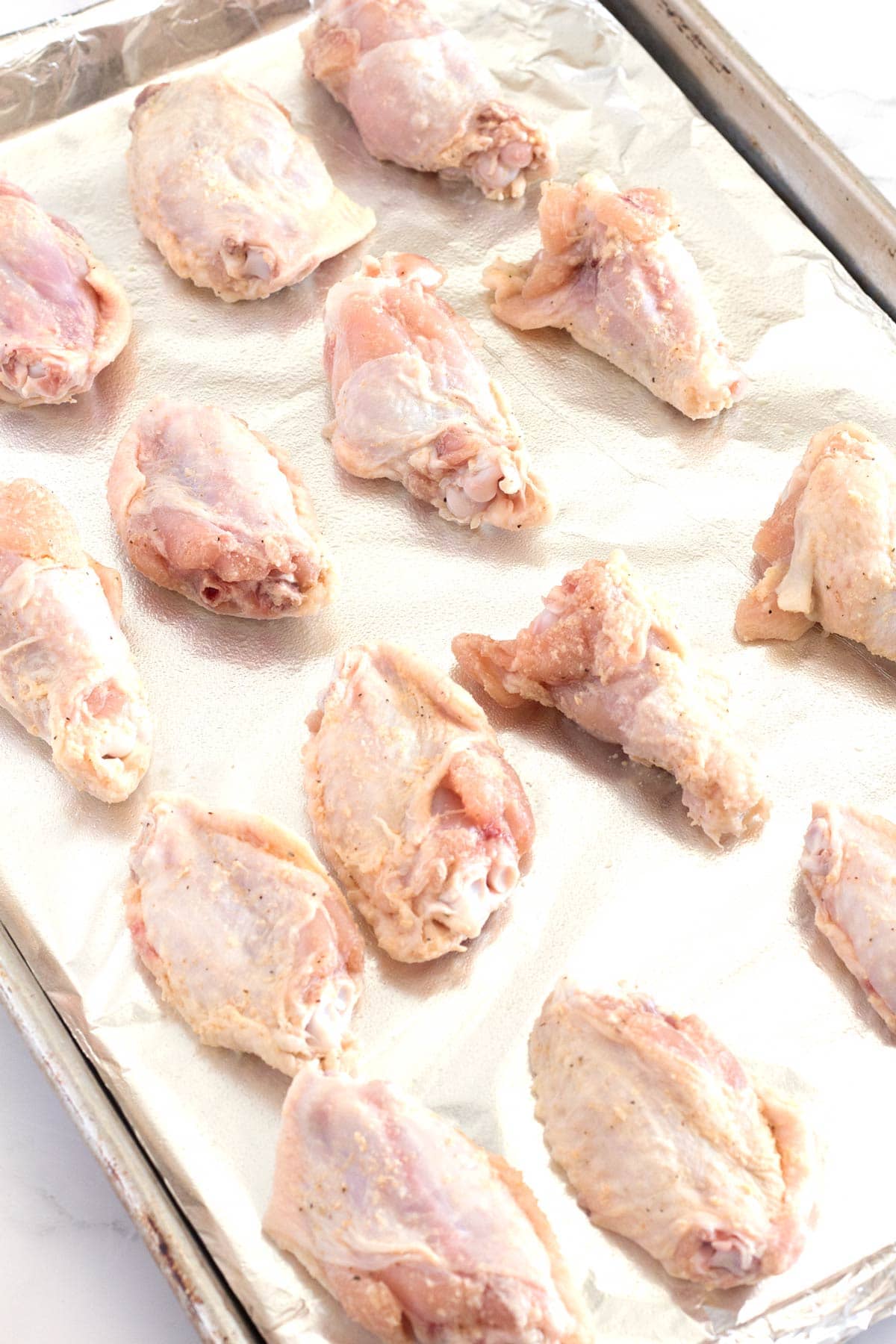 Wings on rimmed baking sheets before getting baked in the oven.