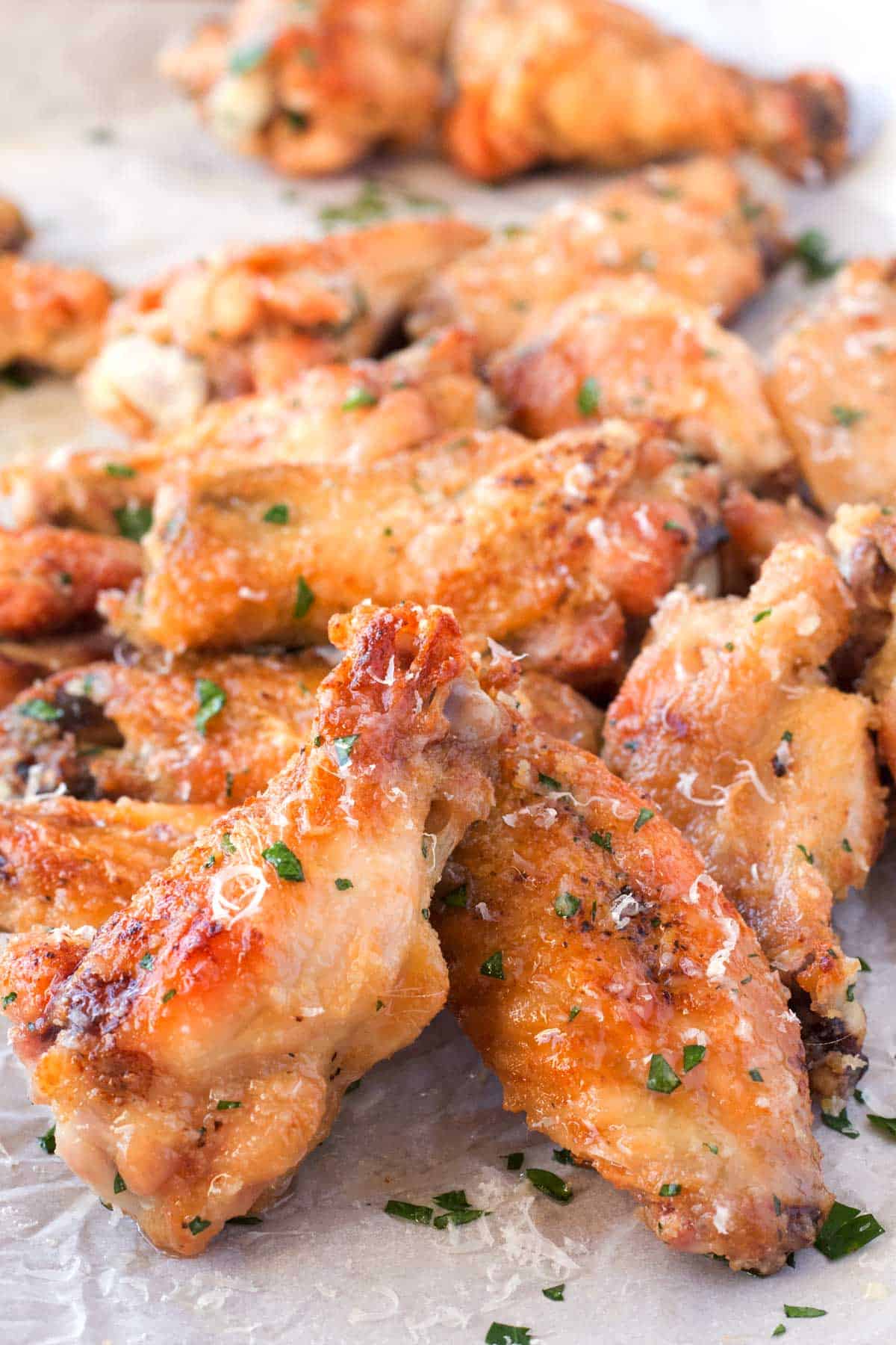 Parchment paper with garlic parmesan chicken wings that are crispy oven baked.