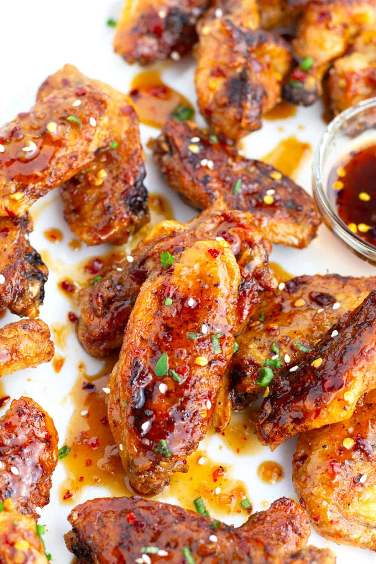 Chicken wings covered in a sweet chili sauce sprinkled with green onions.