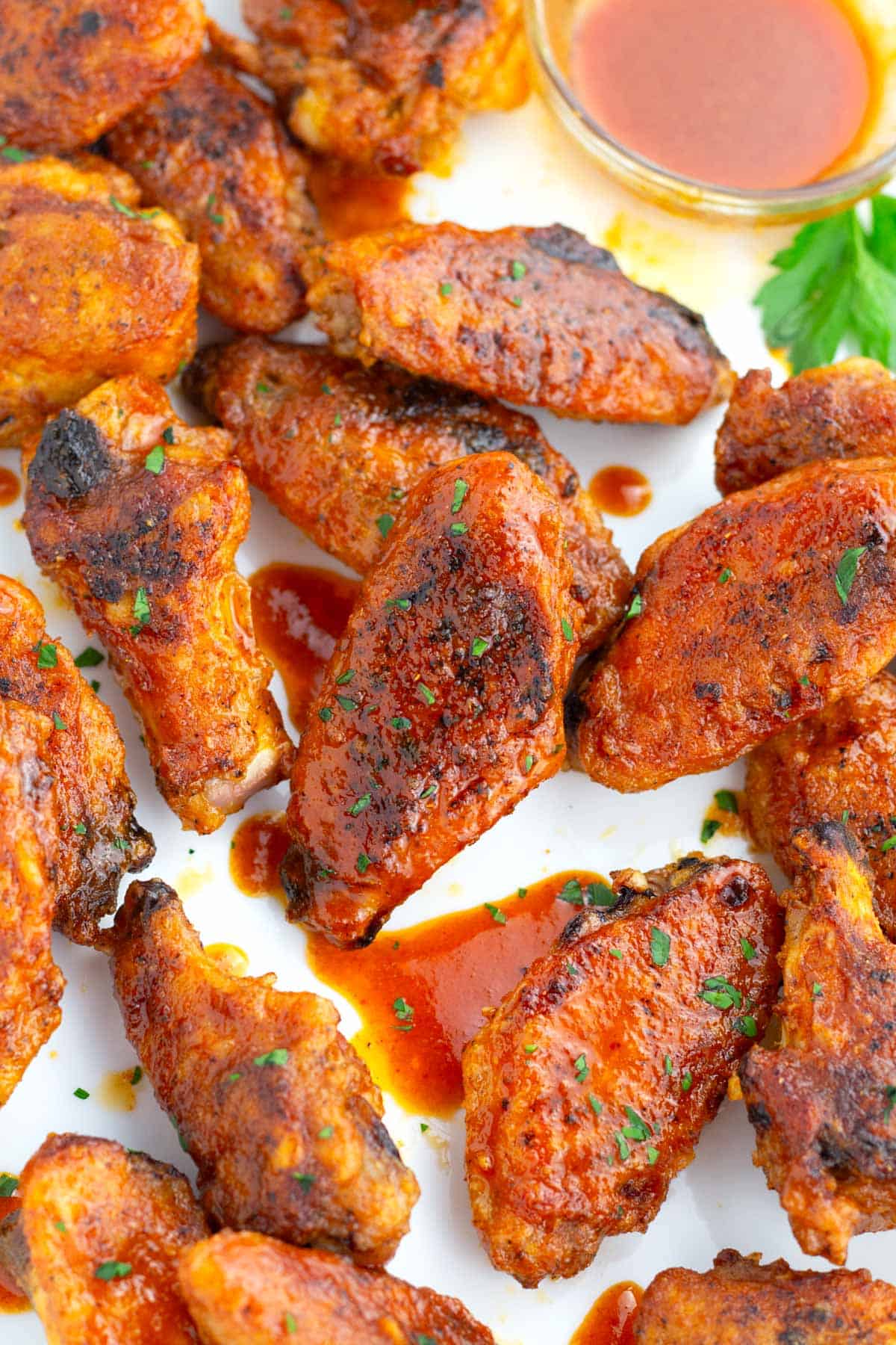 Crispy baked chicken wings tossed in homemade buffalo sauce on a white serving platter.