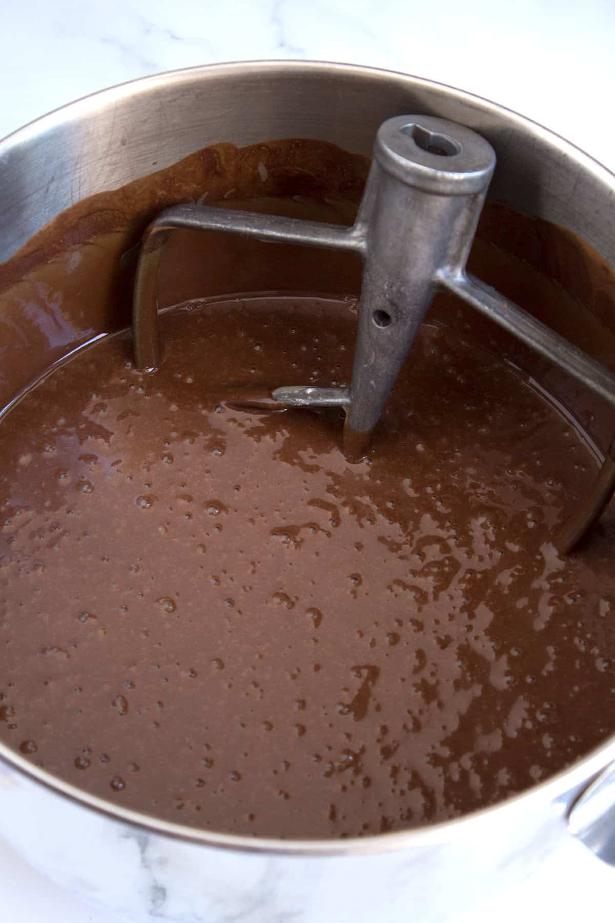 Chocolate cake batter in a mixing bowl with the paddle attachment in the bowl.