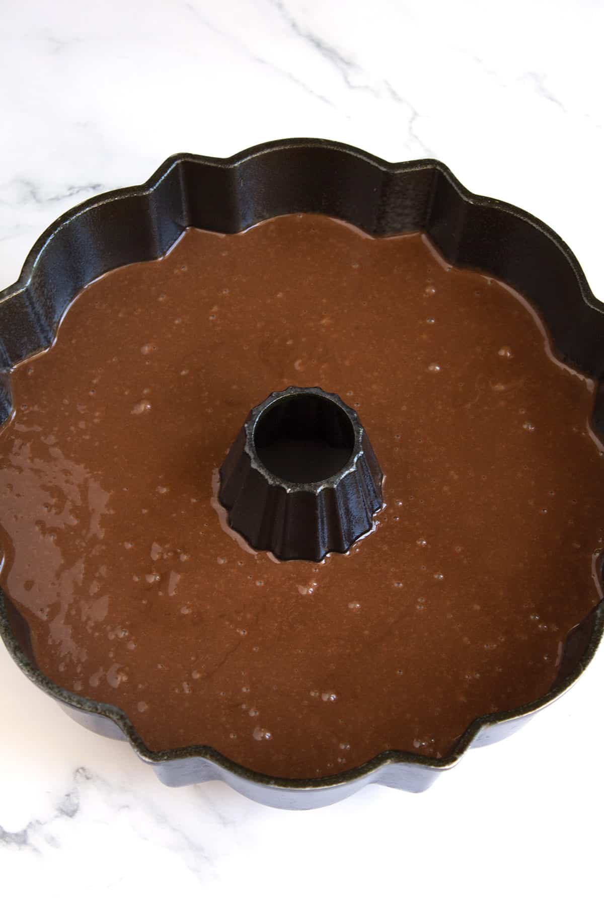 Chocolate cake batter in a bundt cake pan on the counter.