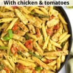 A black skillet full of chicken pesto pasta with tomatoes and veggies, with a green towel on the side of the pan and text overlay on the top of the image.