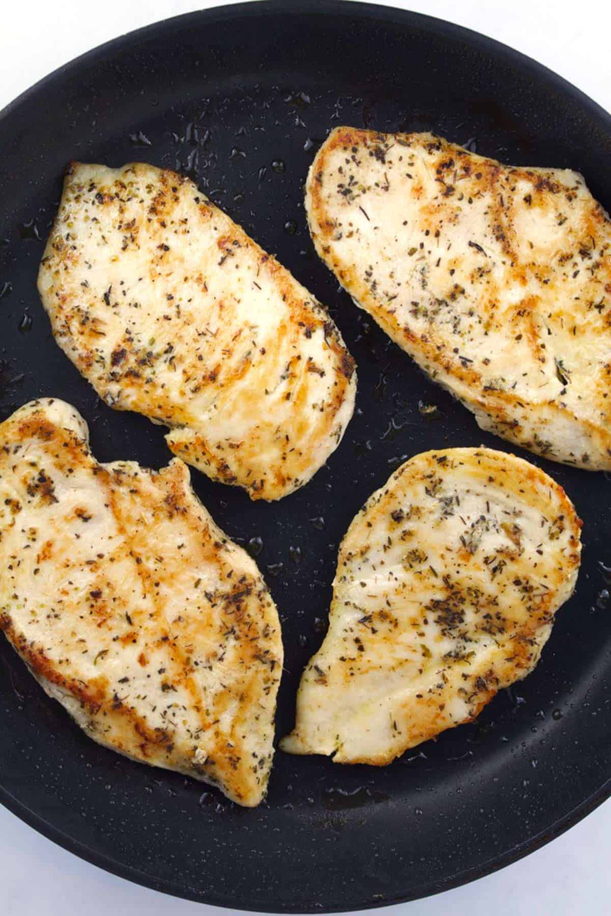Overhead view of a black skillet with golden brown, seasoned chicken.
