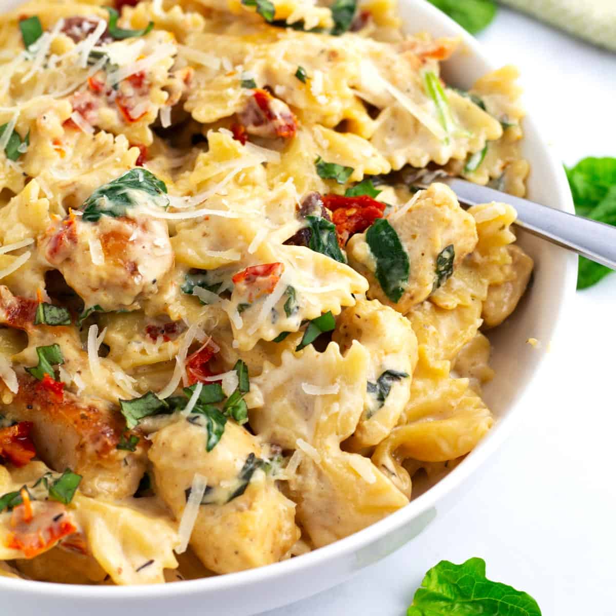 Marry Me Chicken Pasta filled with tender chicken, sun-dried tomatoes, basil, and parmesan cheese in a creamy sauce on serving plate.