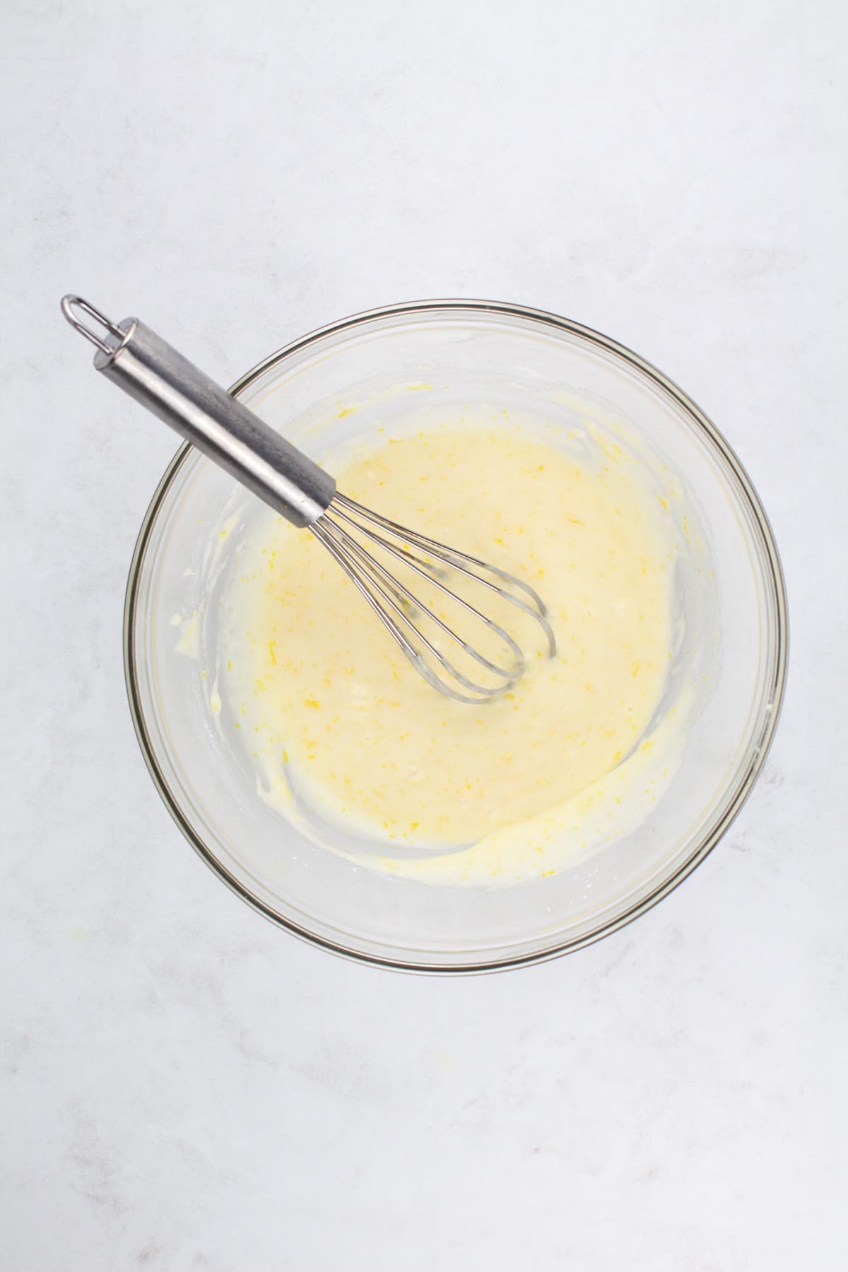 Ingredients for lemon glaze including powdered sugar, lemon juice, and heavy cream mixed in a bowl.