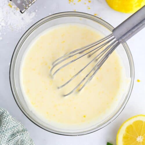 Fresh lemon glaze ingredients in glass bowl on counter with lemon zest.