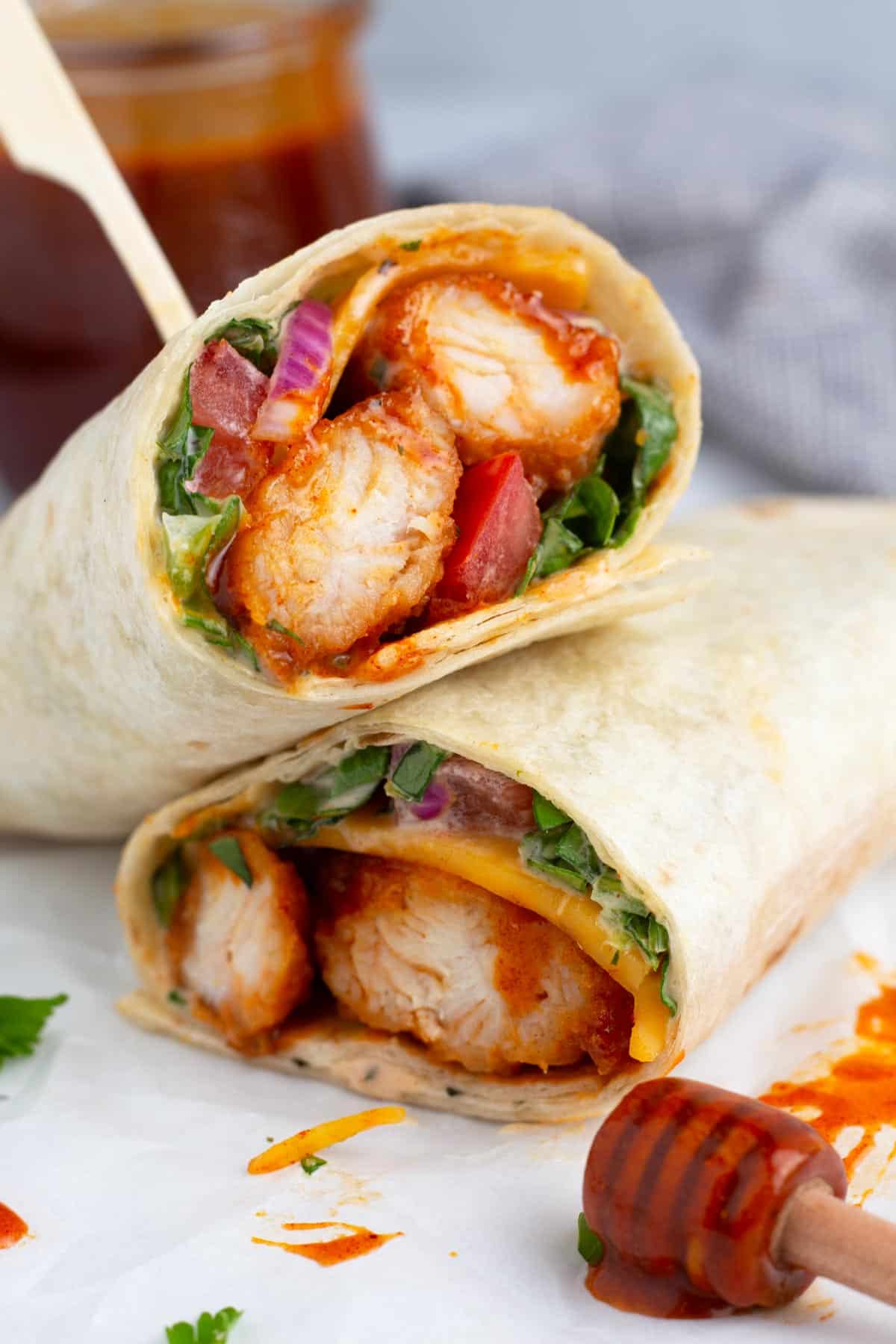 Quick chicken wrap with hot honey sauce angled on top of each other.