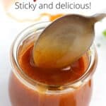 A very close view of the top of a jar of spicy honey glaze with a silver spoon dipping into the jar and text overlay on the top of the image.