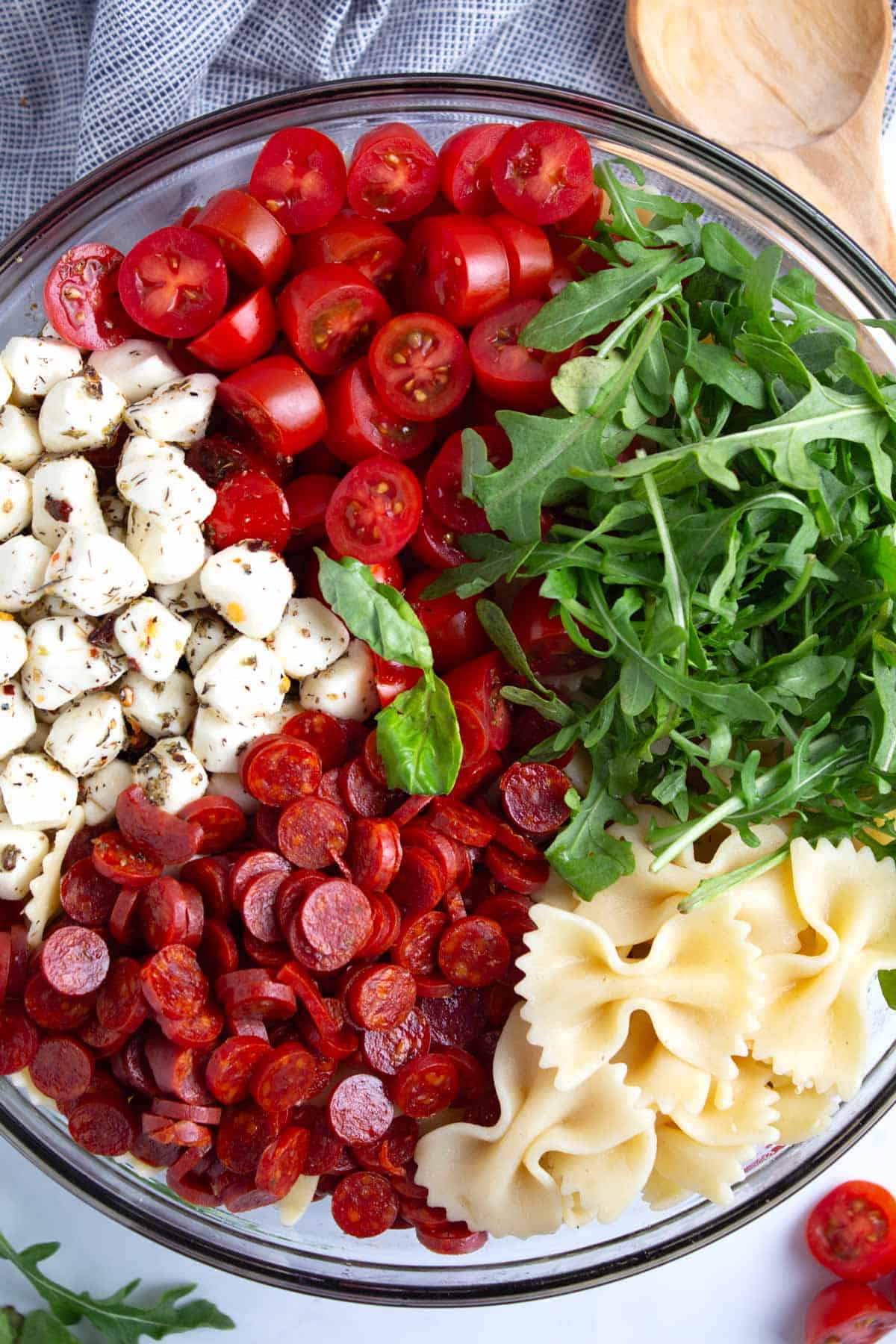 Piles of pasta salad ingredients in bowl before tossing in hot honey vinaigrette.